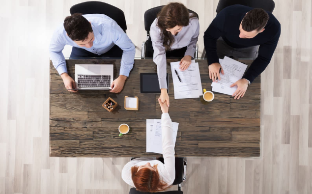 Top view of consultancy business people at a table with laptops, engaged in a productive meeting.