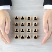 Two Hands holding wooden cubes with human symbols on them indicate candidate sourcing.
