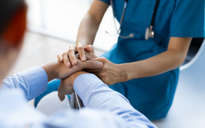 A healthcare professional holding a patient's hand, providing support and reassurance.